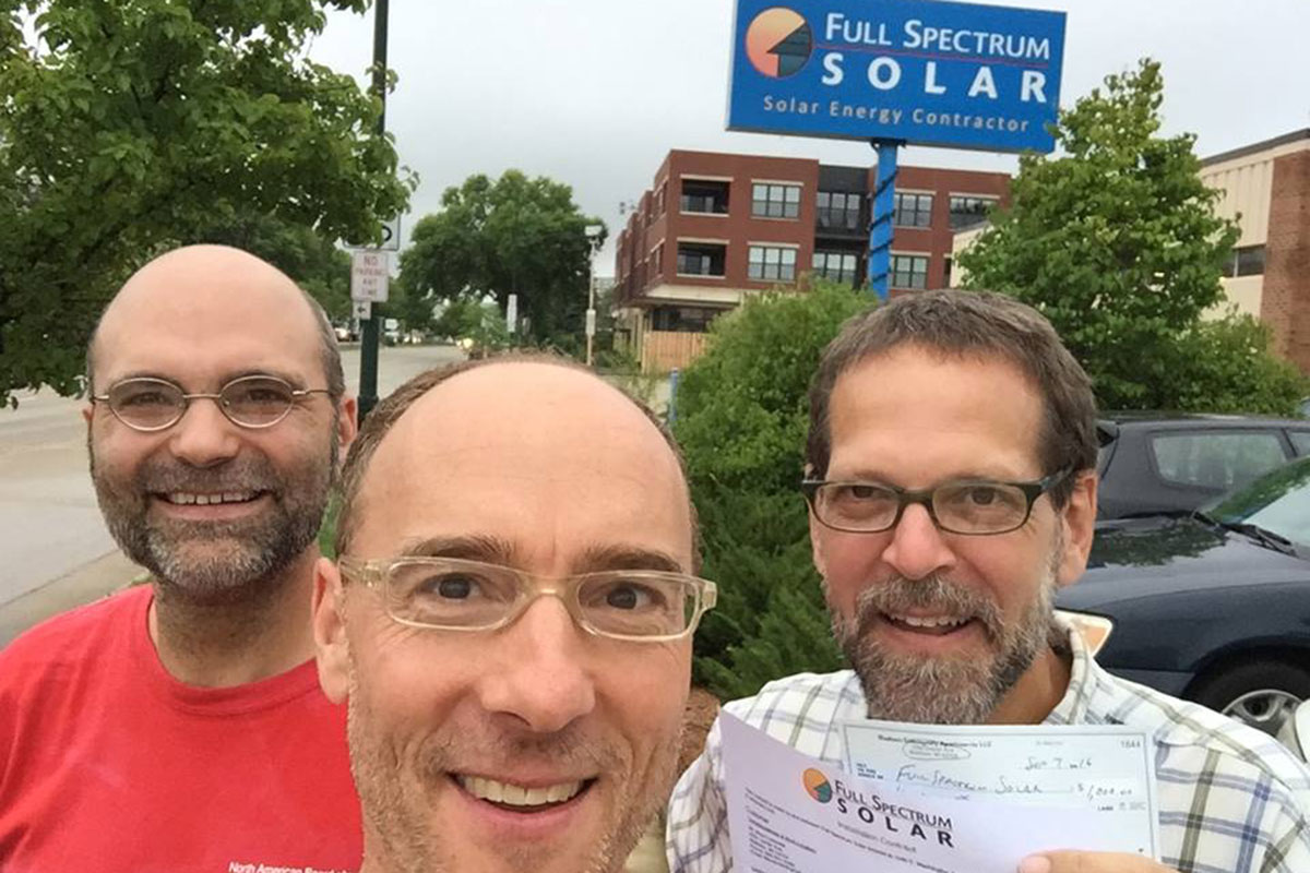 Brian Lavendel and friends smiling in front of blue Full Spectrum Solar sign